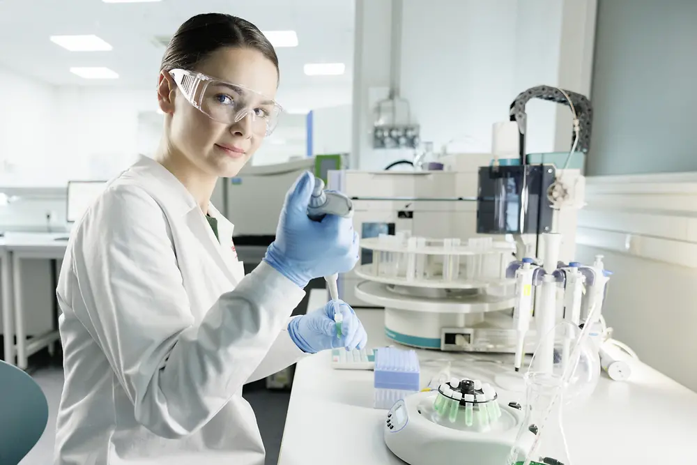 一位穿着白大褂，戴着护目镜女科学家正在实验室里做实验。