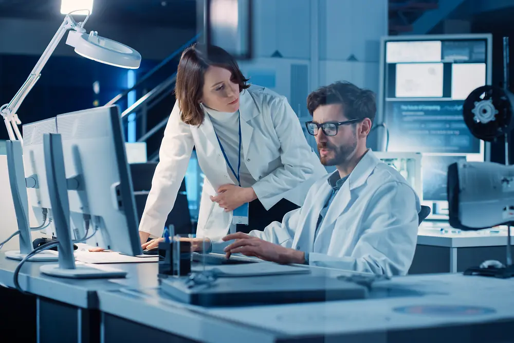 创新伙伴关系：一位男子和一位女子在实验室中看着电脑屏幕
