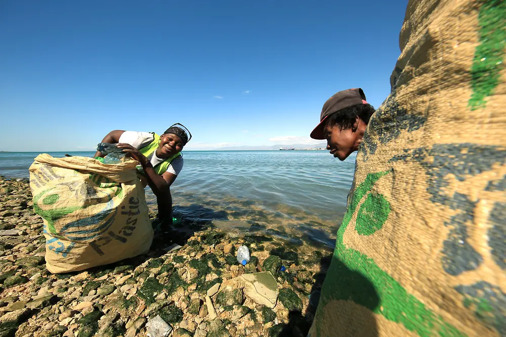 塑料银行项目：两个人在海滩上收集塑料