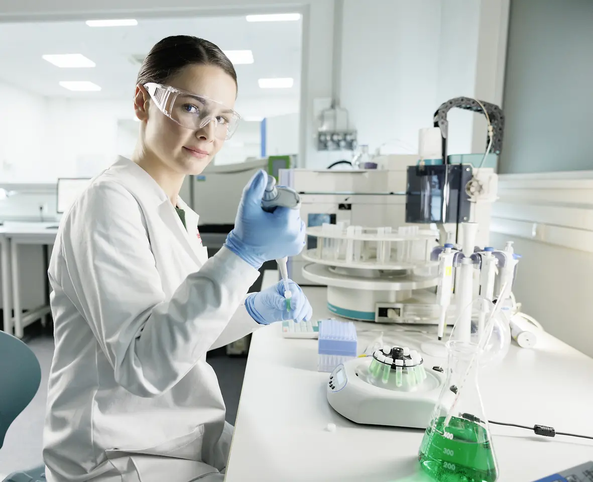 一位穿着白大褂，戴着护目镜女科学家正在实验室里做实验。