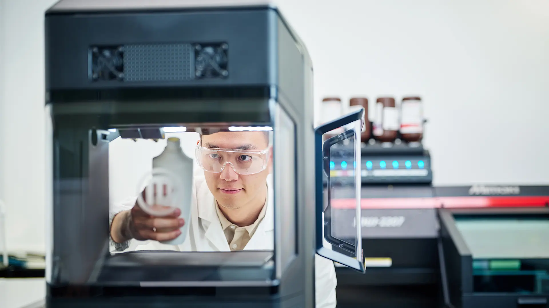 A man taking a shampoo bottle from the 3D printing machine